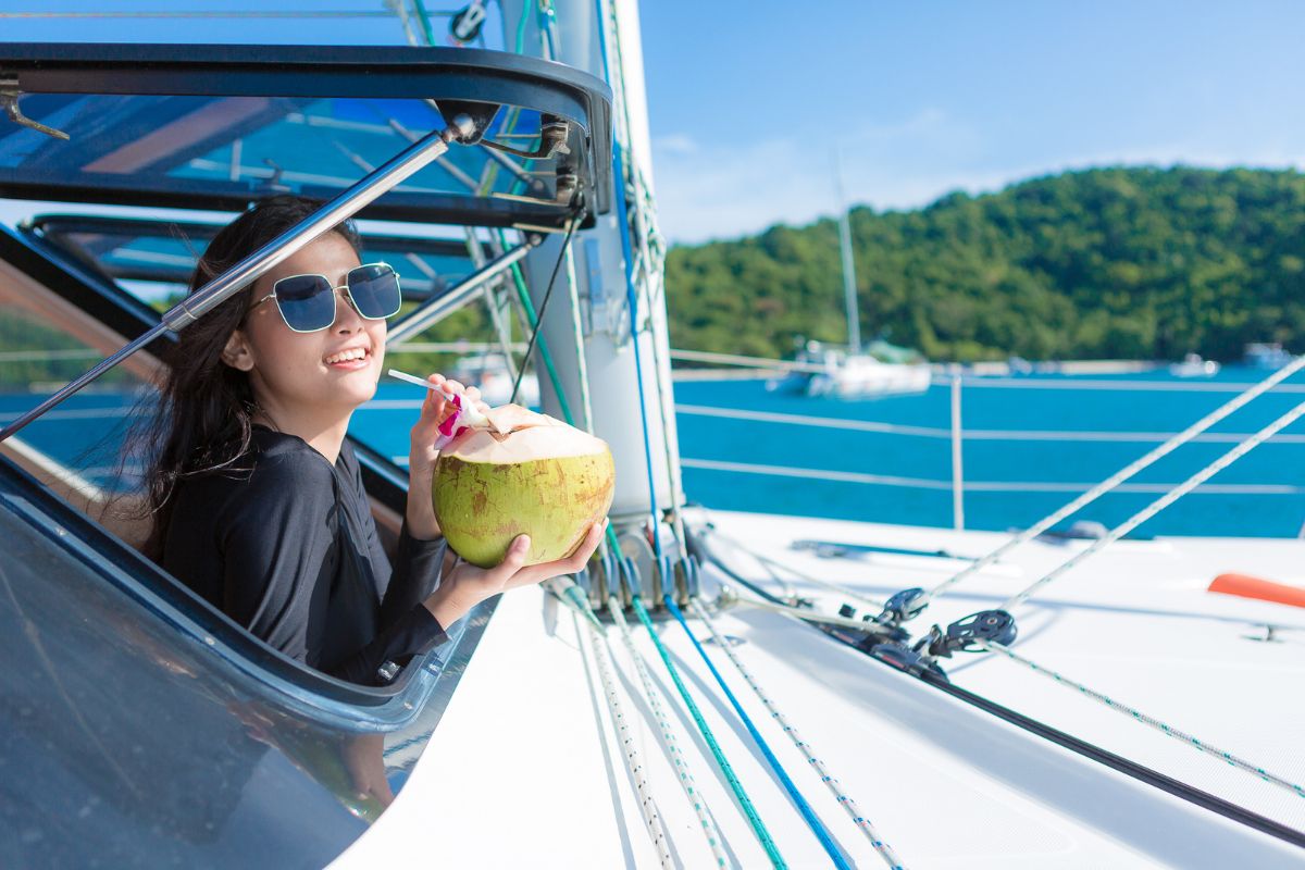 Woman drinking coconut water on the yacht