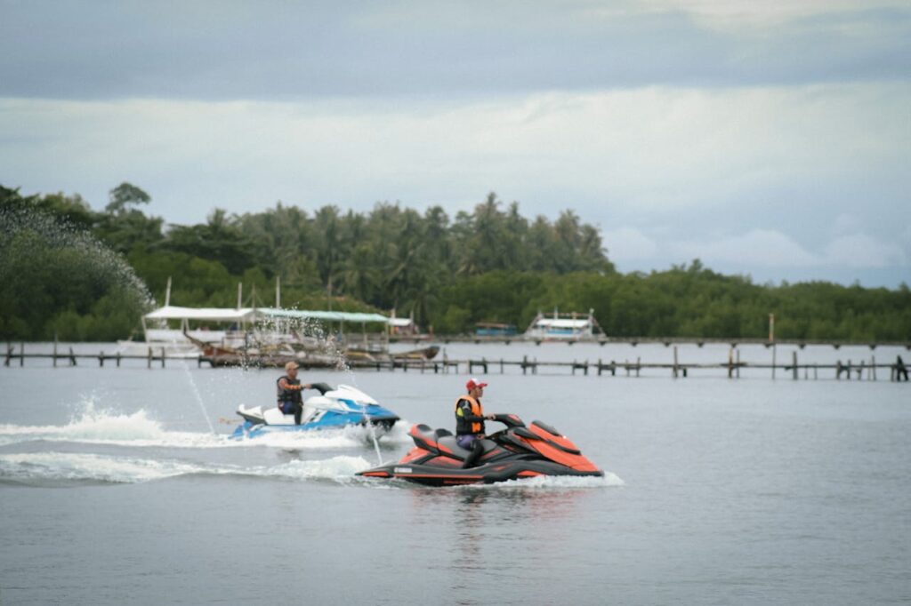 2 men jet skiing slowly, making small waves