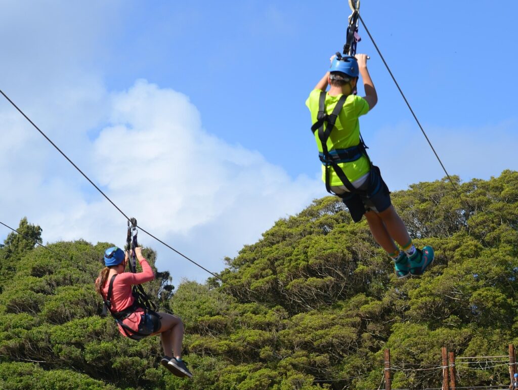 2 people ziplining against blue sky