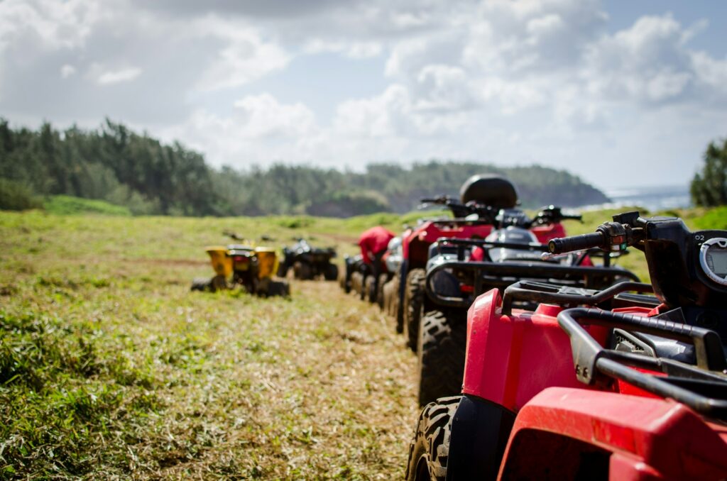 a row of empty ATVs parked in a line on a grassy field