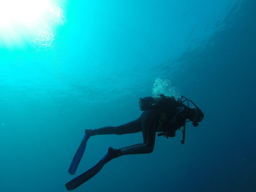 A solo person diving into the vast, clear blue ocean, surrounded only by water