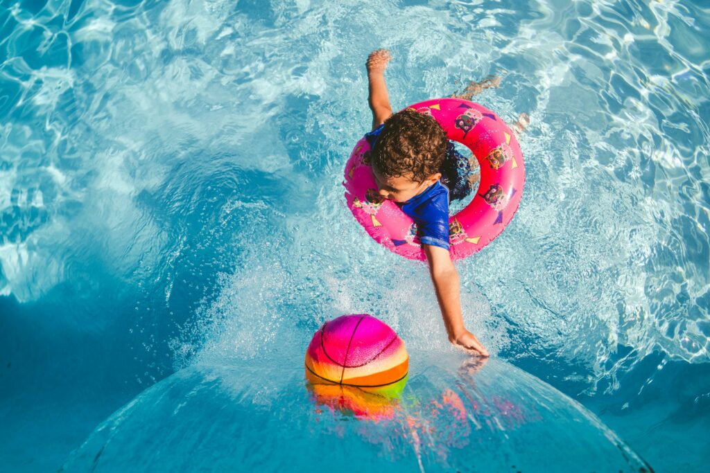 kid in a swim ring playing basketball at water park